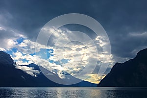 Mountain lake with dramatic clouds in stormy sky at blue twilight