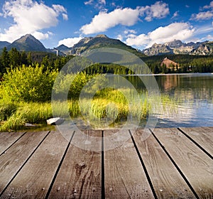 Mountain lake and empty wooden deck table