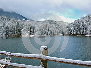 Mountain lake with forest around covered with snow