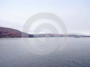 Mountain lake before misty sunset in Higland in Scotland. Snowy cone of mountain above mirroring water photo