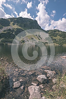 Pohled na panorama horského jezera v pozdním létě ve slovenských Karpatských Tatrách s odrazy skalnatých kopců ve vodě. Roháčské plesa