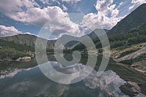 Mountain lake panorama view in late summer in Slovakian Carpathian Tatra with reflections of rocky hills in water. Rohacske plesa