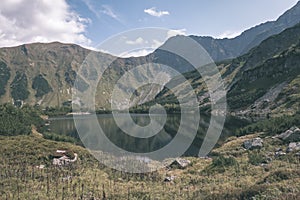 Mountain lake panorama view in late summer in Slovakian Carpathian Tatra with reflections of rocky hills in water. Rohacske plesa