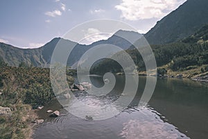 Mountain lake panorama view in late summer in Slovakian Carpathian Tatra with reflections of rocky hills in water. Rohacske plesa