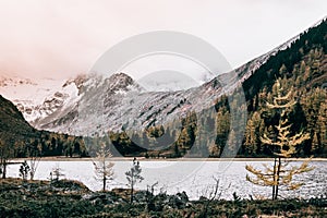 Mountain lake with reflection in the mirrored surface of the rocks in cloudy rainy weather.