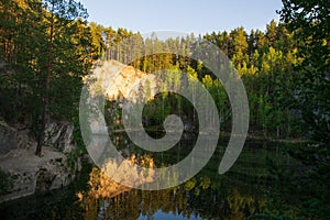 Mountain lake with reflection in the water against the background of the forest and the rays of the setting sun