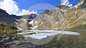 Horské jazero na jar s mohutným skalnatým hrebeňom v pozadí