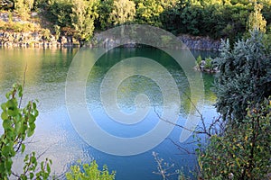 Mountain lake in the summer. Panoramic view on old flooded granite quarry with radon water.