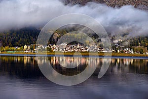 Mountain lake at sunrise in autumn. Landscape with lake, gold sunlight, blue fog over the water, reflection, trees with colorful