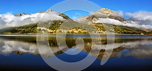 Mountain lake at sunrise in autumn. Landscape with lake, gold sunlight, blue fog over the water, reflection, trees with colorful