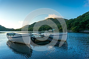 Mountain lake sunrise landscape with two traditional fishing boats