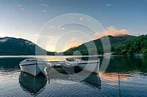 Mountain lake sunrise landscape with two traditional fishing boats