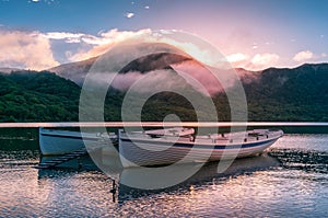 Mountain lake sunrise landscape with two traditional fishing boats