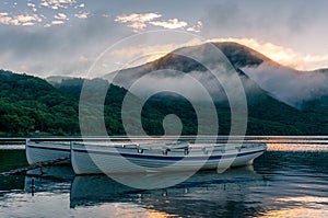 Mountain lake sunrise landscape with two traditional fishing boats