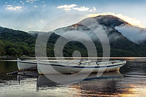 Mountain lake sunrise landscape with two traditional fishing boats