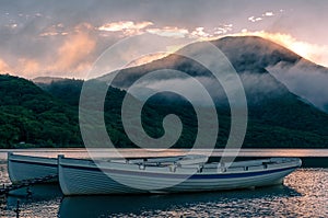 Mountain lake sunrise landscape with two traditional fishing boats