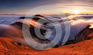 Mountain landscape above clouds at sunset in Slovakia with forest and sun