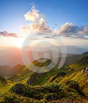 Mountain landscape with beautiful sunrise, cloudy sky and orange colorful horizon. Spring sunny morning. Wallpaper background.