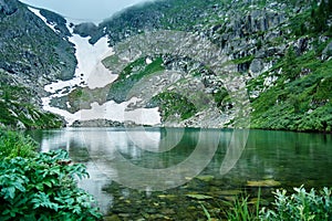 Mountain landscape. Blue lake and snowfield on the shore