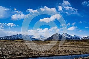 Mountain landscape with bright sky blue, field of gold, glacier and stream