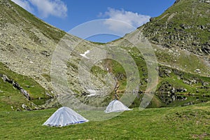 Mountain landscape with camping tents near the lake.
