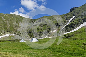 Mountain landscape with camping tents under the summit