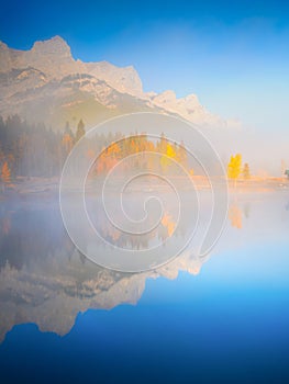 Mountain landscape at dawn. Foggy morning. Lake and forest in a mountain valley at dawn.