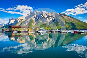 Mountain landscape at the day time. Boats near the pier. Lake and forest in a mountain valley.