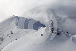 Mountain landscape. Fog and clouds on top. Snow-covered slopes.