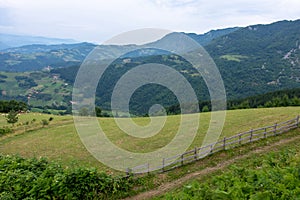 Mountain Landscape and Green Meadow with Blue Cloudy Sky