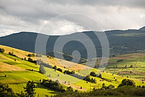 Mountain landscape with green and yellow grass and haystacks