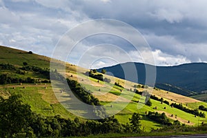 Mountain landscape with green and yellow grass and haystacks