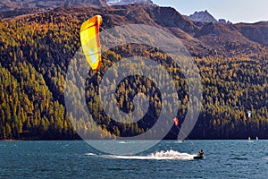 Mountain landscape with a lot of kite surfers and windsurfers moving in a lake