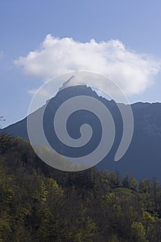 Mountain landscape with peak and cloud on a bright sunny spring day with green vegetation and blue sky in Picos de Europa