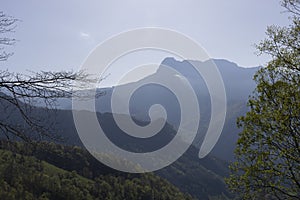 Mountain landscape with peak and cloud on a bright sunny spring day with green vegetation and blue sky in Picos de Europa National