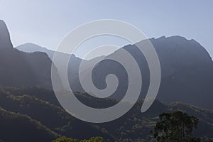 Mountain landscape with peak and cloud on a bright sunny spring day with green vegetation and blue sky in Picos de Europa National