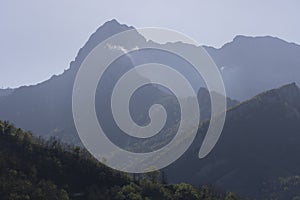 Mountain landscape with peak and cloud on a bright sunny spring day with green vegetation and blue sky in Picos de Europa National