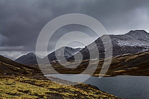 Mountain landscape. Rocky shore of a mountain lake on a rainy autumn day. First snow