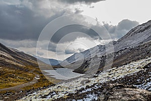 Mountain landscape. Rocky shore of a mountain lake on a rainy autumn day. First snow