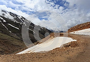 Mountain landscape with snow peaks with melting snow and clouds