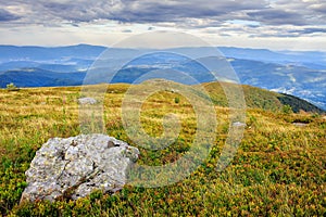 Mountain landscape with stones in the grass on hillside and blue