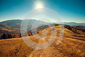 Mountain landscape on a sunny autumn day. View of the mountain slopes and dirt road