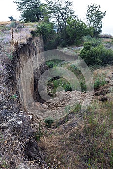 Mountain landslide disaster in sesmically dangerous area. Large cracks in earth, descent of large layers of earth blocking road. M