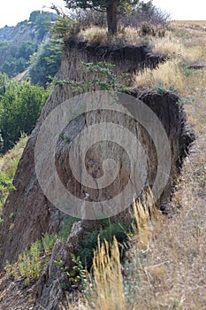 Mountain landslide disaster in sesmically dangerous area. Large cracks in earth, descent of large layers of earth blocking road. M