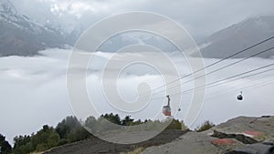Mountain lift with mountain view with clouds. Creative. Cable car with moving funiculars in snowy mountains. Beautiful