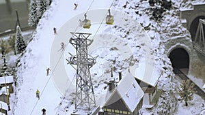 Mountain lift on ski slope with skiers. Miniature model railroad track