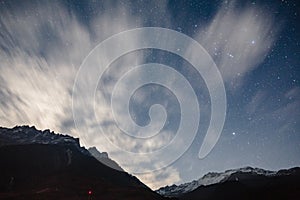 Mountain with little snow on the top and moving cloud in the blue color night with stars in winter at Lachung in North Sikkim.