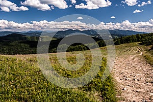 Mountain meadow with hills on the background and blue sky with clouds photo