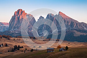 Mountain meadow and house Alpe di Siusi or Seiser Alm in the background Langkofel mountain range at sunset with Province of