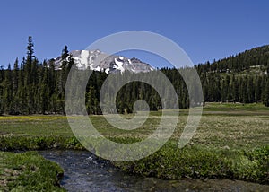 Mountain Meadow with a Stream Against Blue Sky